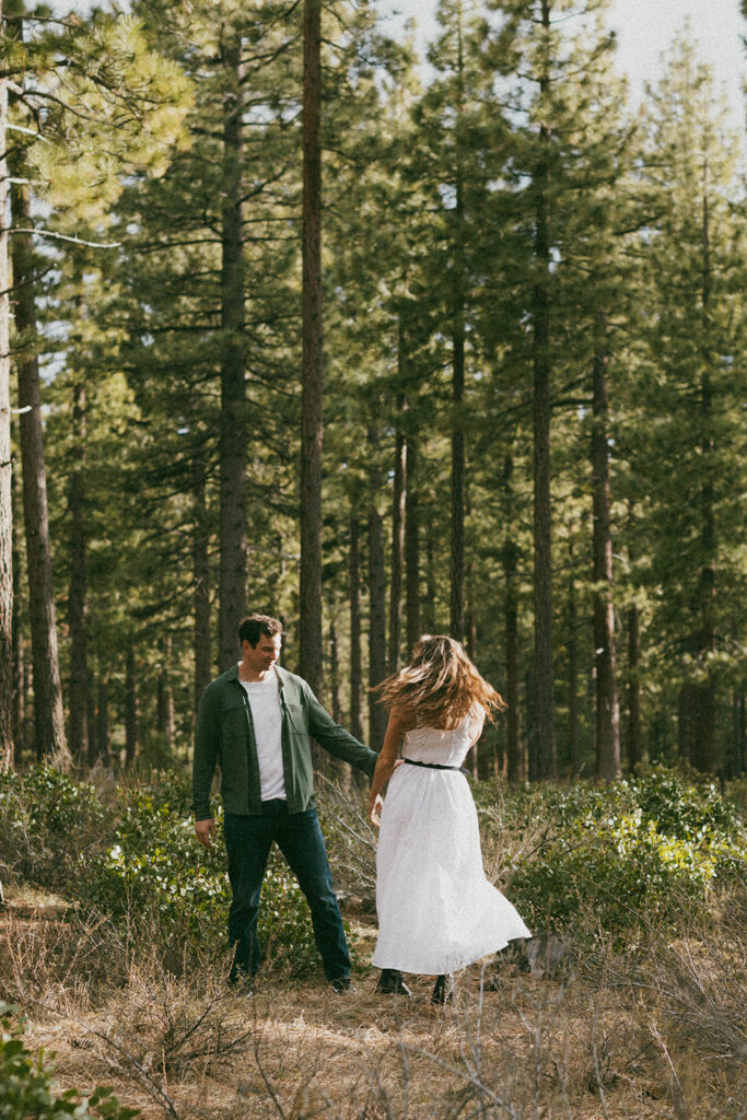 man and woman in white dress spin in woods of Khale Park Nevada