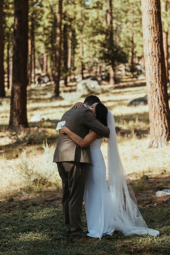 man and woman in white dress hug in woods of Khale Park Nevada