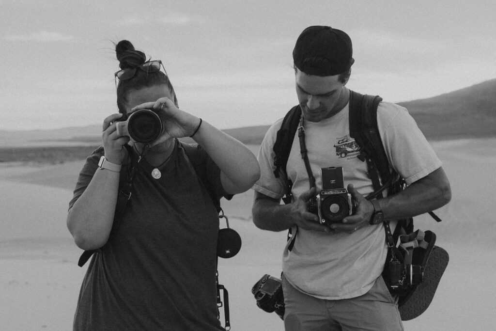 Black and white photo of a couple holding film cameras. 